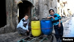 FILE - Boys are pictured beside a cart they use to carry water back to their home in the east Aleppo neighborhood of al-Mashatiyeh, Syria, in this handout picture provided by UNHCR, Jan. 4, 2017. 