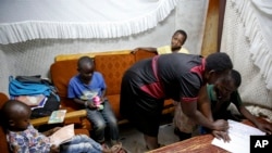 FILE - Students of St Dominic Bukna Secondary school take their English test outside due to their overcrowded class room in Kisumu, Kenya.