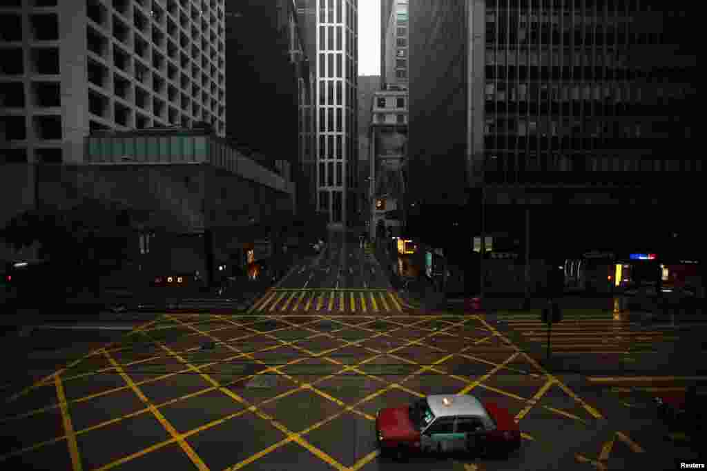 A taxi drives across an empty street in Hong Kong's central business district as Typhoon Vicente approaches, July 24, 2012. 