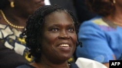 FILE - Simone Gbagbo, Ivory Coast's former first lady, smiles as she sits in the dock at the Court of Justice in Abidjan on Dec. 26, 2014, for the start of her trial.