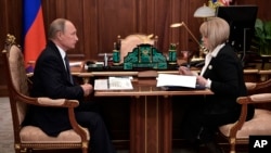 Russian President Vladimir Putin (L) listens to Ella Pamfilova, head of Russian Central Election Commission during their meeting in Moscow, Russia, Oct. 9, 2017.