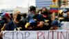 Peserta demo menentang aksi invasi Rusia terhadap Ukraina di luar kantor Uni Eropa di Caracas Venezuela, membentangkan spanduk yang bertuliskan "Hentikan Putin" pada 3 Maret 2022. (Foto: Reuters/Leonardo Fernandez Viloria)